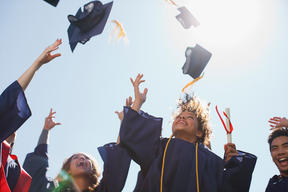 happy graduates tossing caps in the air in celebration